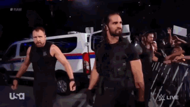 a group of wrestlers are standing on a stage in front of a police car .