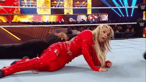 a woman in a red wrestling outfit is laying on the floor in a wrestling ring .