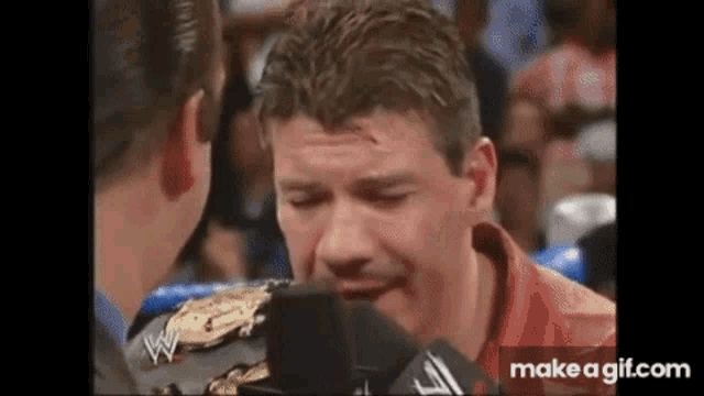 a man in a red leather jacket is talking into a microphone .