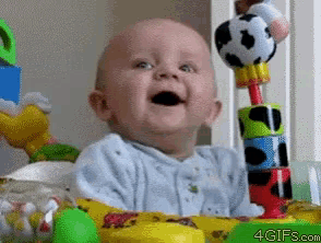 a baby is smiling while sitting in a crib with toys and the website 4gifs.com is visible in the corner