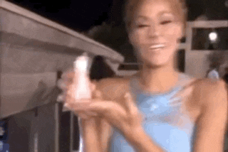 a woman in a blue dress is holding a bottle of lotion .