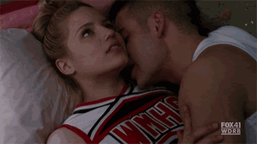 a cheerleader is kissing a man who is wearing a white tank top that says fox 41 wdrb