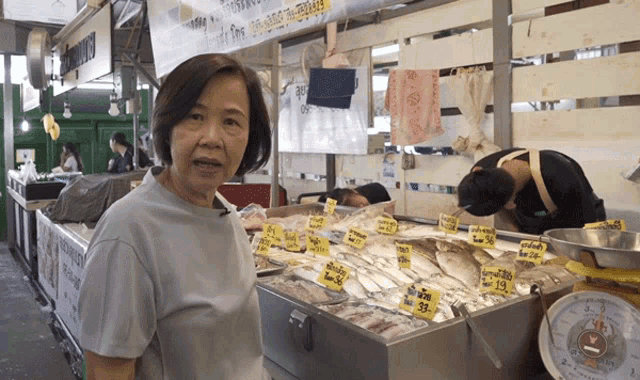 a woman standing in front of a display of fish with a sign that says ' a ' on it