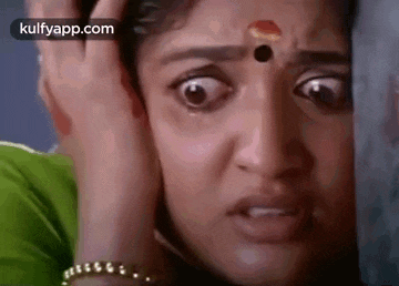 a close up of a woman making a funny face with her hands on her head .