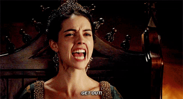 a woman with a tiara on her head is sitting in a chair saying get out