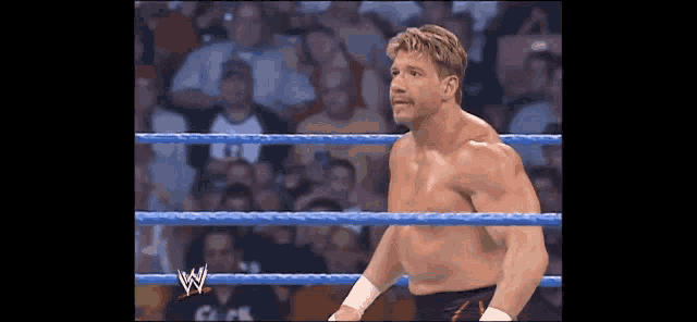 a shirtless wrestler in a wrestling ring with the letter w on the ropes