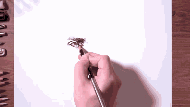 a person drawing an eye with a pencil on a piece of paper