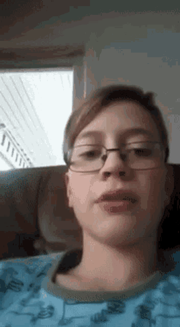 a young boy wearing glasses and a blue shirt is making a funny face .