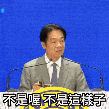 a man in a suit and tie stands at a podium with chinese writing on the bottom