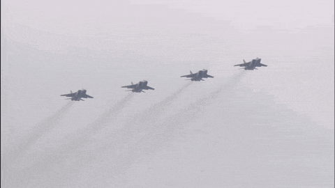 four fighter jets flying in a row with smoke trails behind them