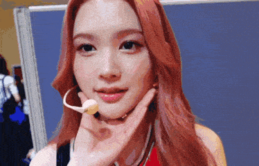 a woman with red hair is wearing a microphone on her neck