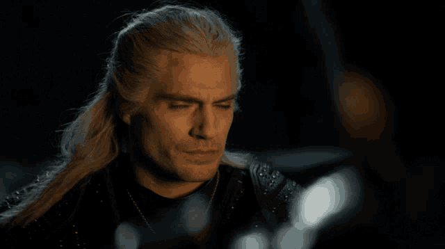a man with long blonde hair is looking at another person