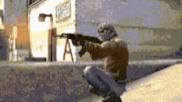 a man in a mask is kneeling down holding a gun .