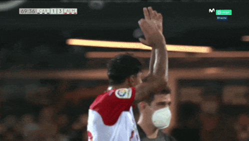 a man in a red and white shirt is raising his fist in the air during a soccer game