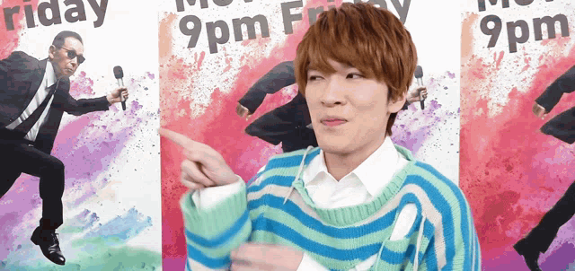 a man in a striped sweater stands in front of a poster that says 9 pm friday