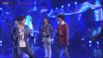a group of men are standing on a stage with microphones