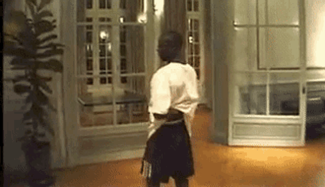 a man is dancing in a living room in front of a window .