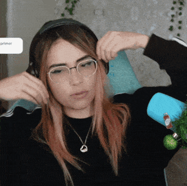 a girl wearing glasses and headphones is sitting in front of a sign that says primer on it