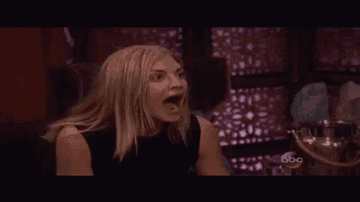 a woman is making a funny face while sitting at a table with her mouth open .