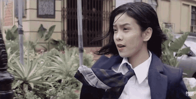 a girl in a school uniform and tie is running down the street .