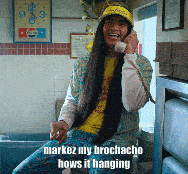 a man with long hair is talking on a phone with the words " marquez my brochacho hows it hanging " above him