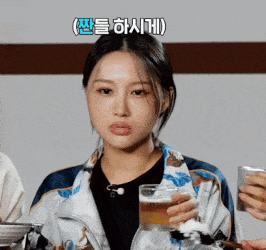 a woman in a jacket holds a glass of beer and a can of soda