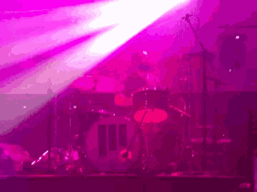 a drum set is lit up in a pink light