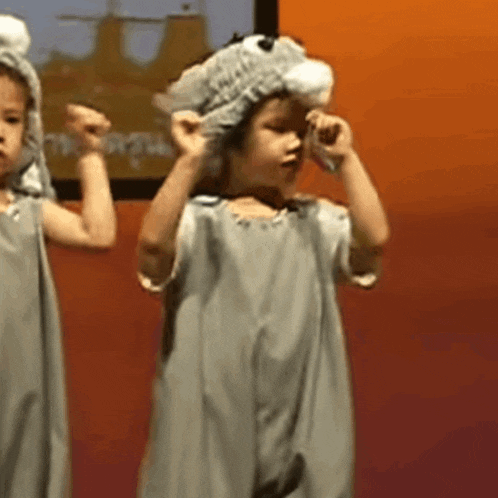 a little girl is wearing a gray dress and hat