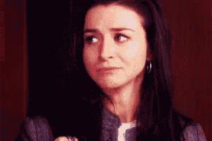 a woman with long dark hair is making a funny face while wearing hoop earrings .