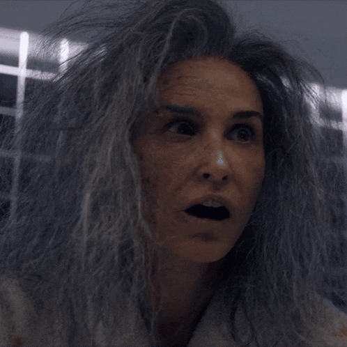 a woman with gray hair and a white robe looks surprised