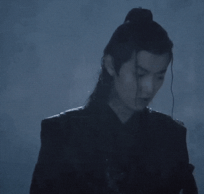 a man with long hair and a ponytail is standing in the rain .
