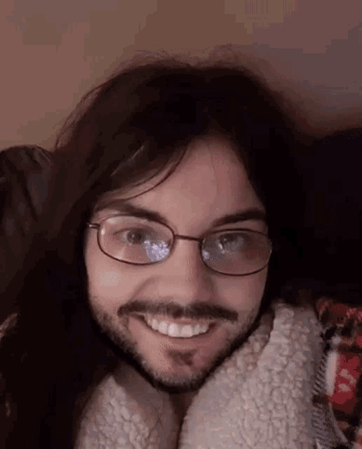 the man is wearing glasses and a beard and smiling .