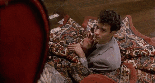 a man is laying on a rug on the floor holding a glass of wine .