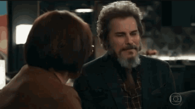 a man with a beard and glasses is talking to a woman .