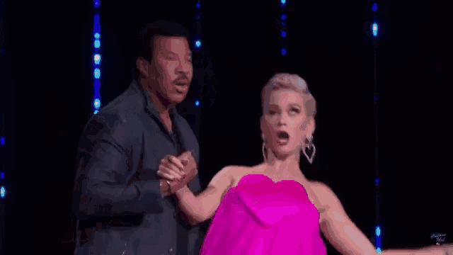 a woman in a pink dress is dancing on a stage with two men watching