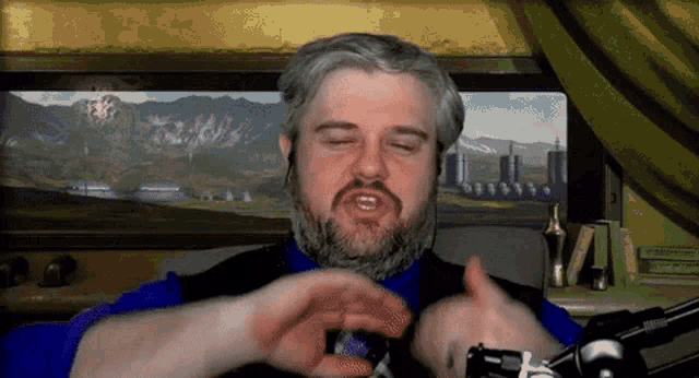 a man with a beard is sitting in front of a microphone
