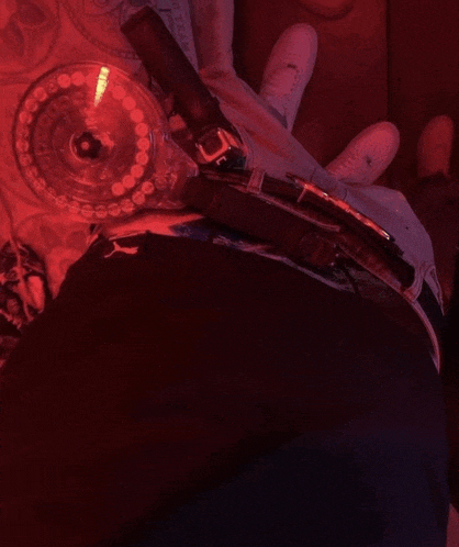 a person is holding a gun in their hand with a red light behind it