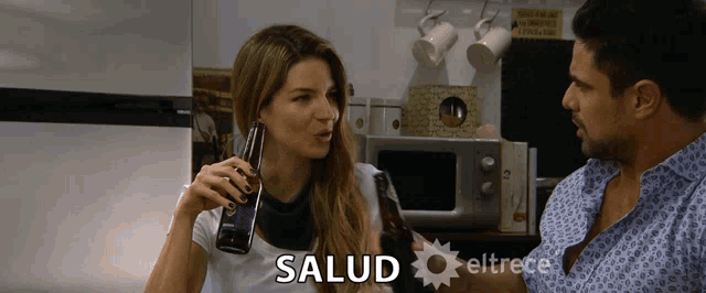 a woman drinking a beer next to a man with salud written on the bottom of the screen
