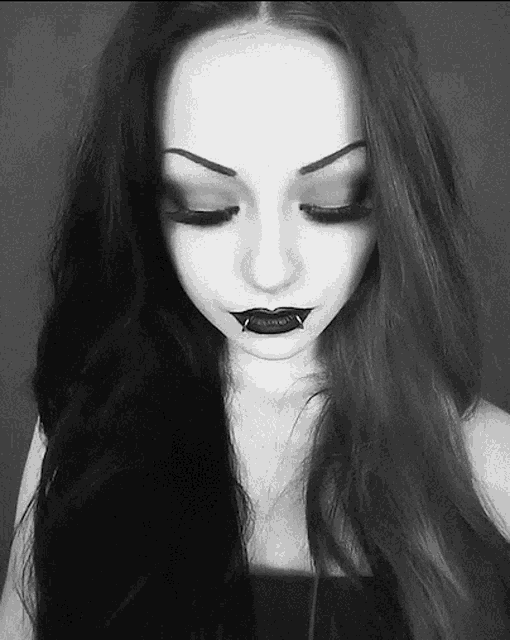 a black and white photo of a woman with vampire teeth in her lips