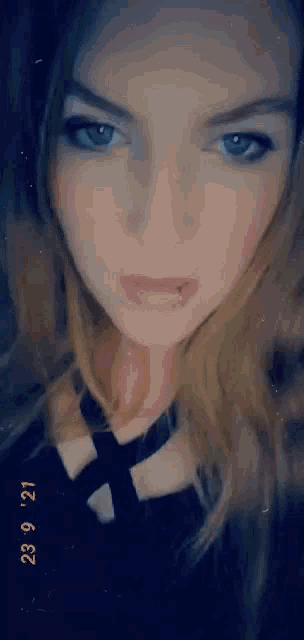 a woman with blue eyes and a piercing in her lip is taking a selfie .
