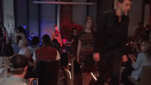 a man in a plaid shirt is walking in front of a crowd of people