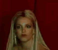 a woman with long blonde hair is making a funny face in front of a red background .