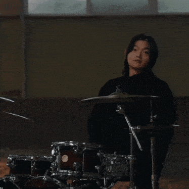 a woman playing a drum set with chinese writing on the bottom right