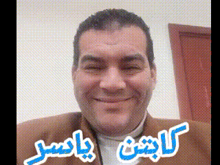 a man in a brown jacket is smiling in front of a door with arabic writing on it