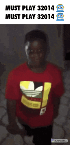 a boy wearing a red adidas shirt stands in front of a sign that says must play 32014