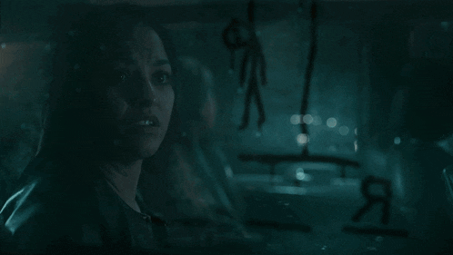 a woman is looking through a window with a drawing of a man hanging from the ceiling