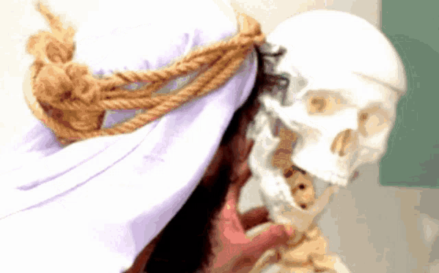 a woman with a rope around her head holds a skull