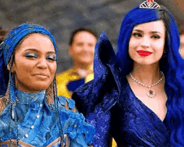 two women are standing next to each other wearing blue dresses .
