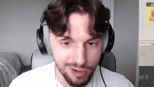 a man wearing headphones looks at the camera in front of a sign that says st ii
