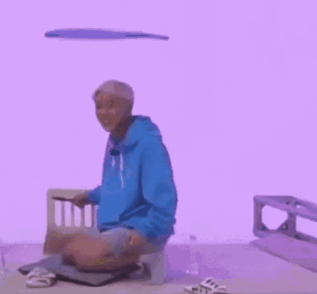 a person wearing a blue hoodie and a yellow hat is kneeling down .
